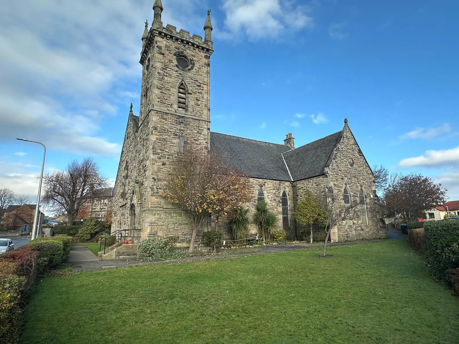 Biserica Sfântul Mina din Kirkcaldy, clădire de piatră cu turn, văzută din grădină